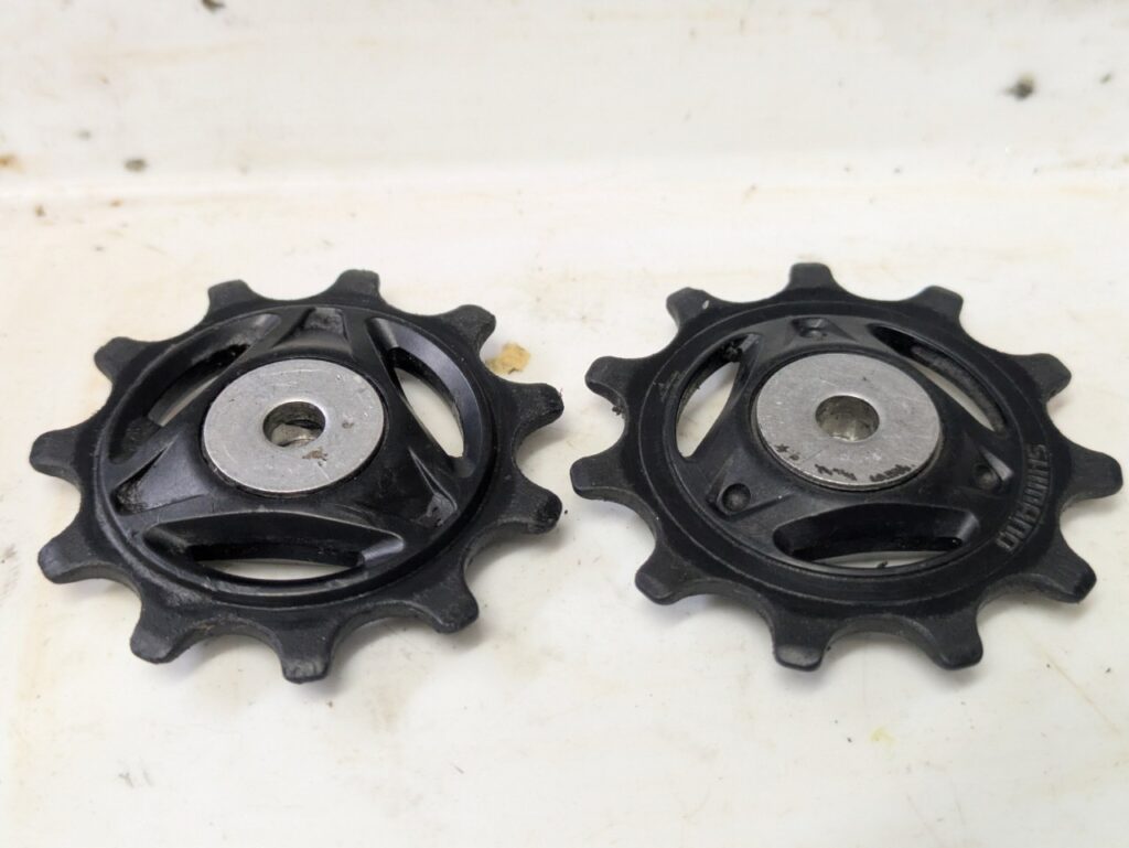 使用済みのSHIMANO 12速プーリーを2個並べて摩耗状態を比較している画像