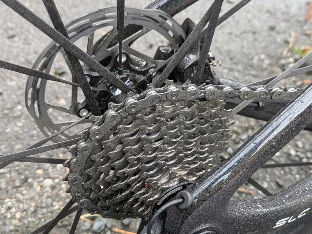 雨天走行後のロードバイクのスプロケットとチェーンに、水分と汚れたオイルが付着している様子。
