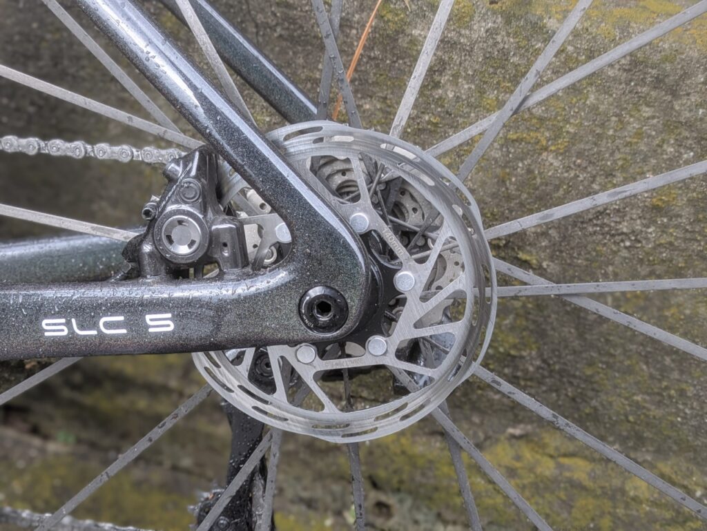 雨天走行後のロードバイクのリアディスクブレーキ周りに水分と細かな汚れが付着している様子。